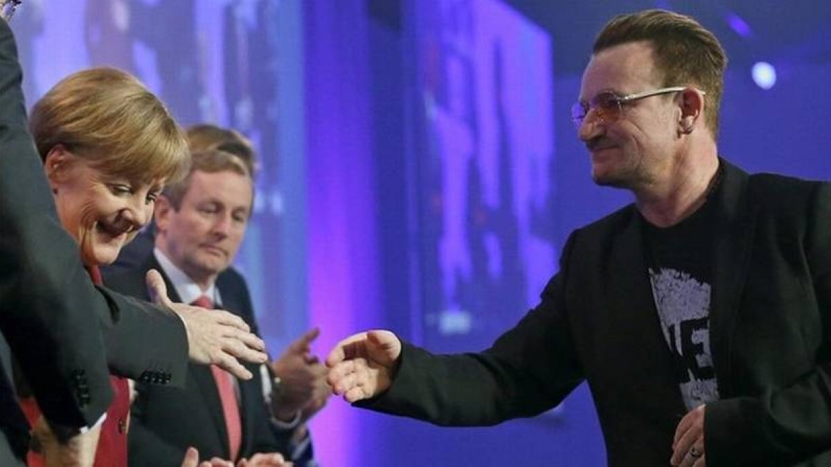 Bono, el cantante de U2, saluda a la cancillera alemana, Angela Merkel, este viernes en la clausura del congreso del PPE.