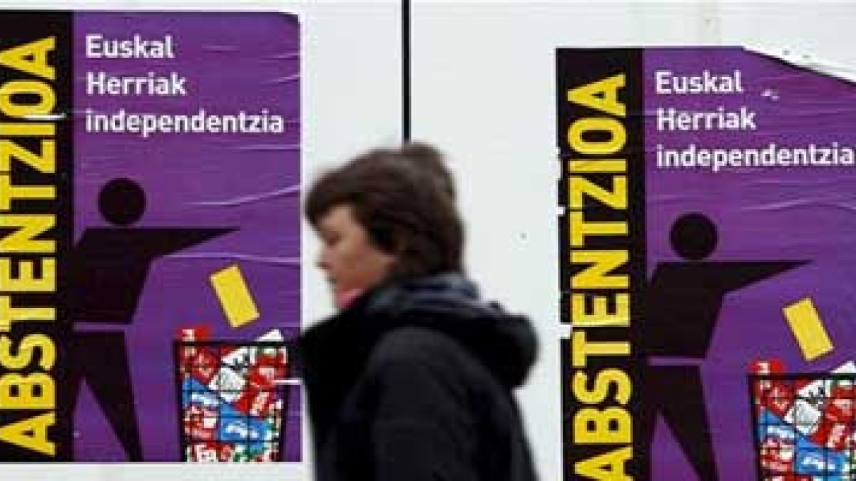 Una mujer pasa ante algunos de los carteles pidiendo la abstención en las elecciones vascas.