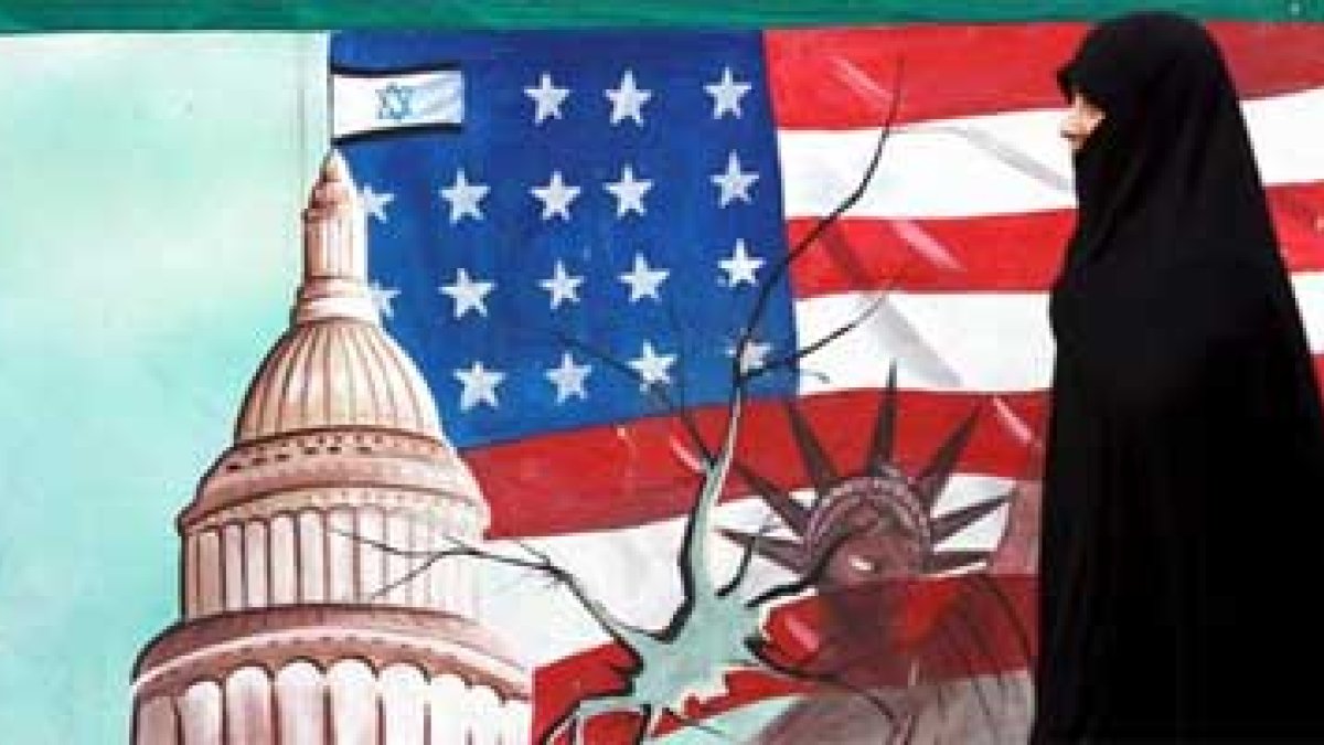 Una mujer iraní pasa junto a un dibujo de la bandera estadounidense.