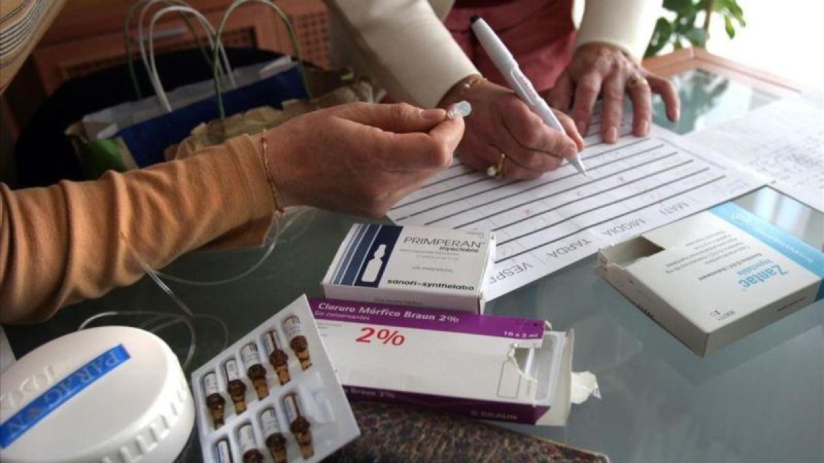 Dos enfermeras preparando los medicamentos para muerte digna en casa de un paciente.
