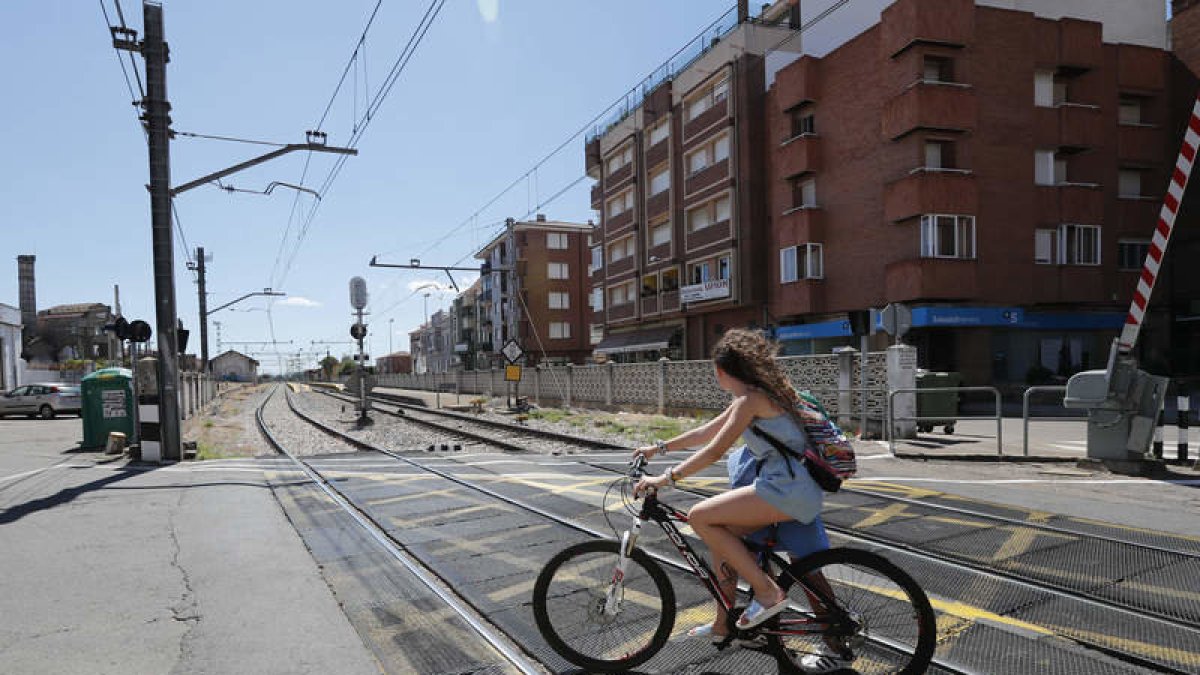Unos ciclistas atravesando un paso a nivel con barreras ubicado en la localidad de Veguellina de Órbigo. JESÚS F. SALVADORES.
