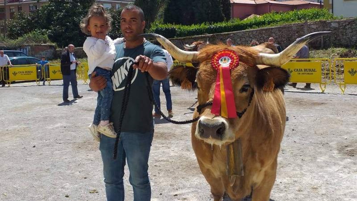 El joven ganadero, con su hija en brazos, junto a una de sus vacas en un reciente concurso. ARAUJO