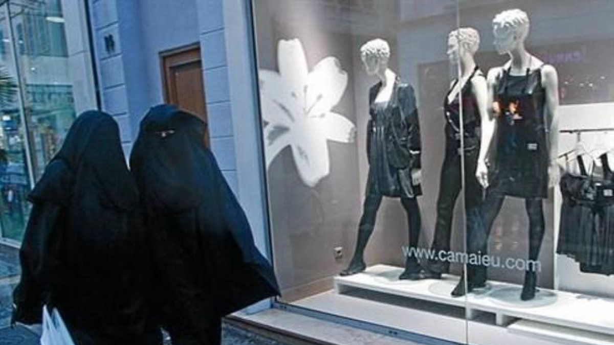Dos mujeres con velo integral, ante un escaparate de ropa en Marsella.