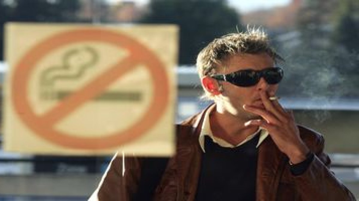 Un hombre fuma a las puertas de un local que prohíbe el tabaco.