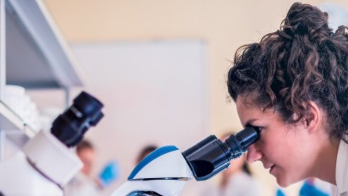 Una investigadora observa desde su microscopio. AECC