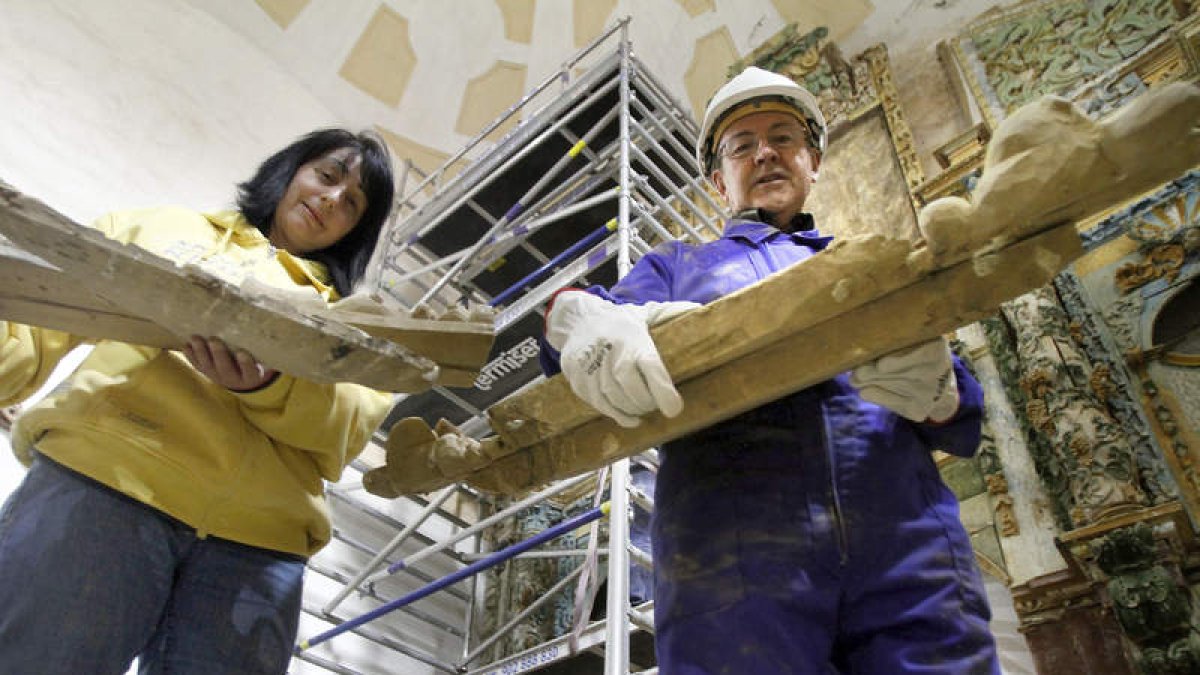 Una vecina de San Pedro y el propio párroco, ayudando a desmontar el gran retablo de la iglesia parroquial