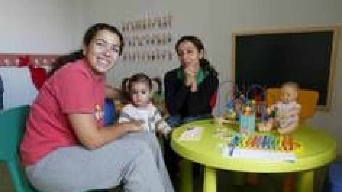Una de las niñas de la nueva guardería de La Virgen, junto a sus dos tutoras
