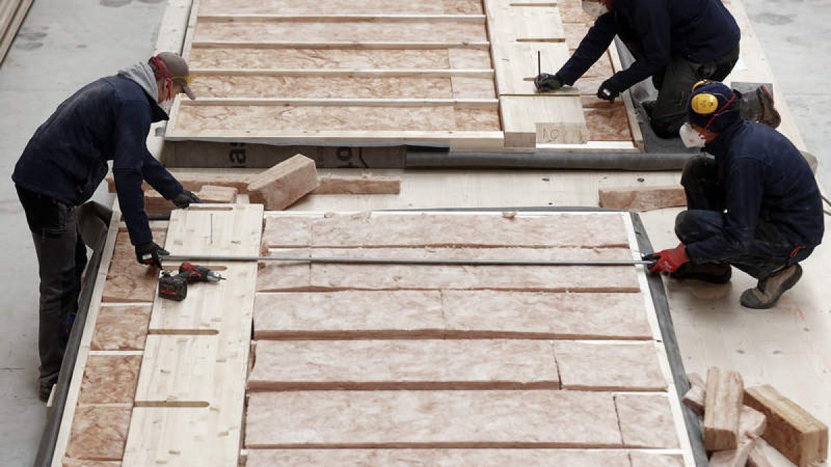 Varios trabajadores terminan de elaborar una pared de madera para su uso. JESÚS DIGES