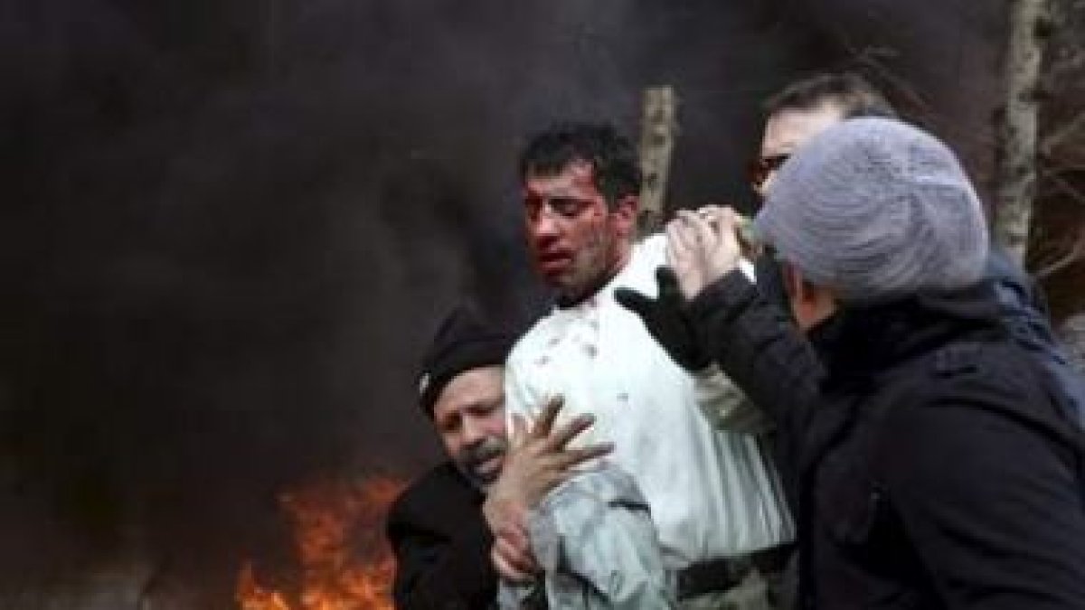 Varias personas ayudan a un policía herido durante las protestas en Irán.