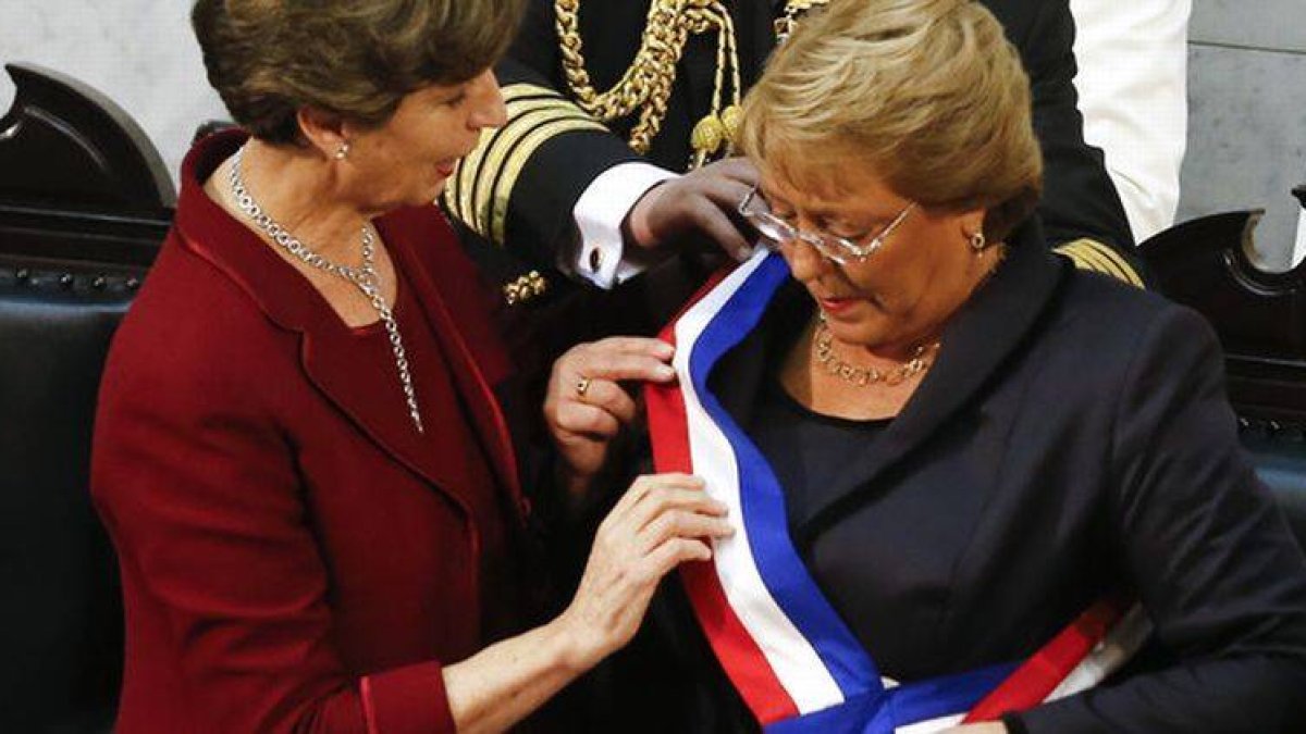 Isabel Allende, hija del presidente derrocado por la dictadura de Pinochet, coloca la banda presidencial a Michelle Bachelet, hija de un militar leal a Allende.