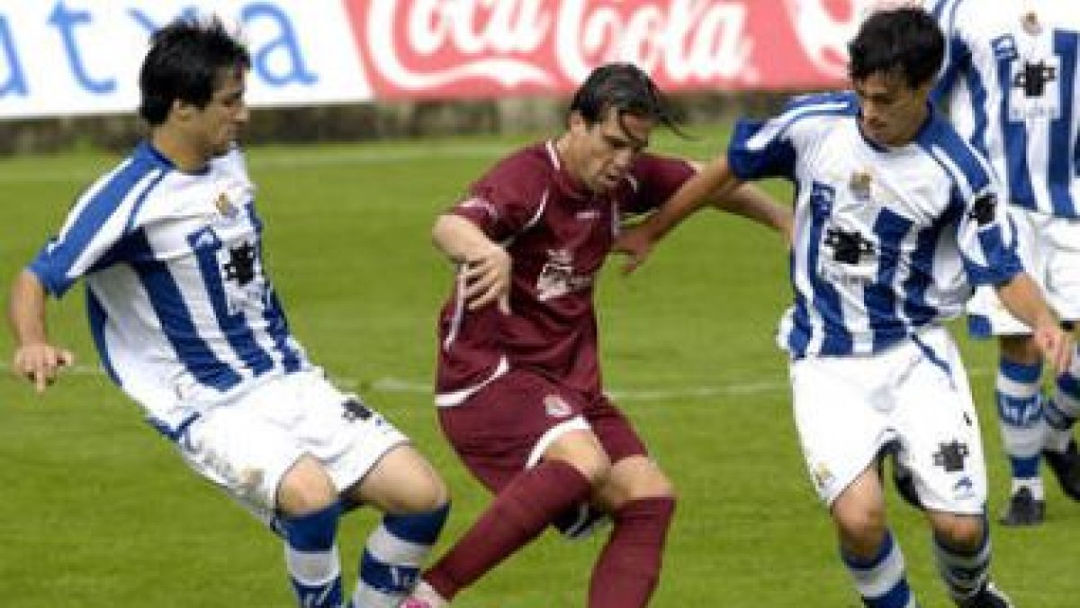 Mena, en el centro de la imagen, se hace con el balón ante dos rivales de la Real Sociedad B.