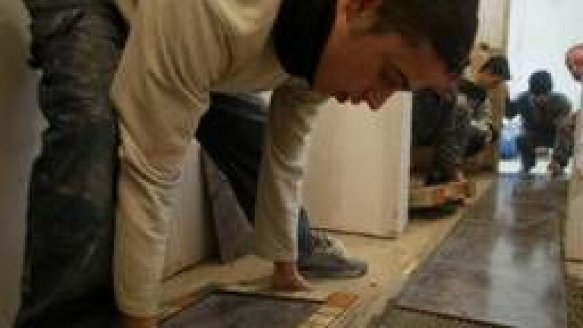 Los jóvenes del taller de albañilería rematan el suelo del apartamento en construcción