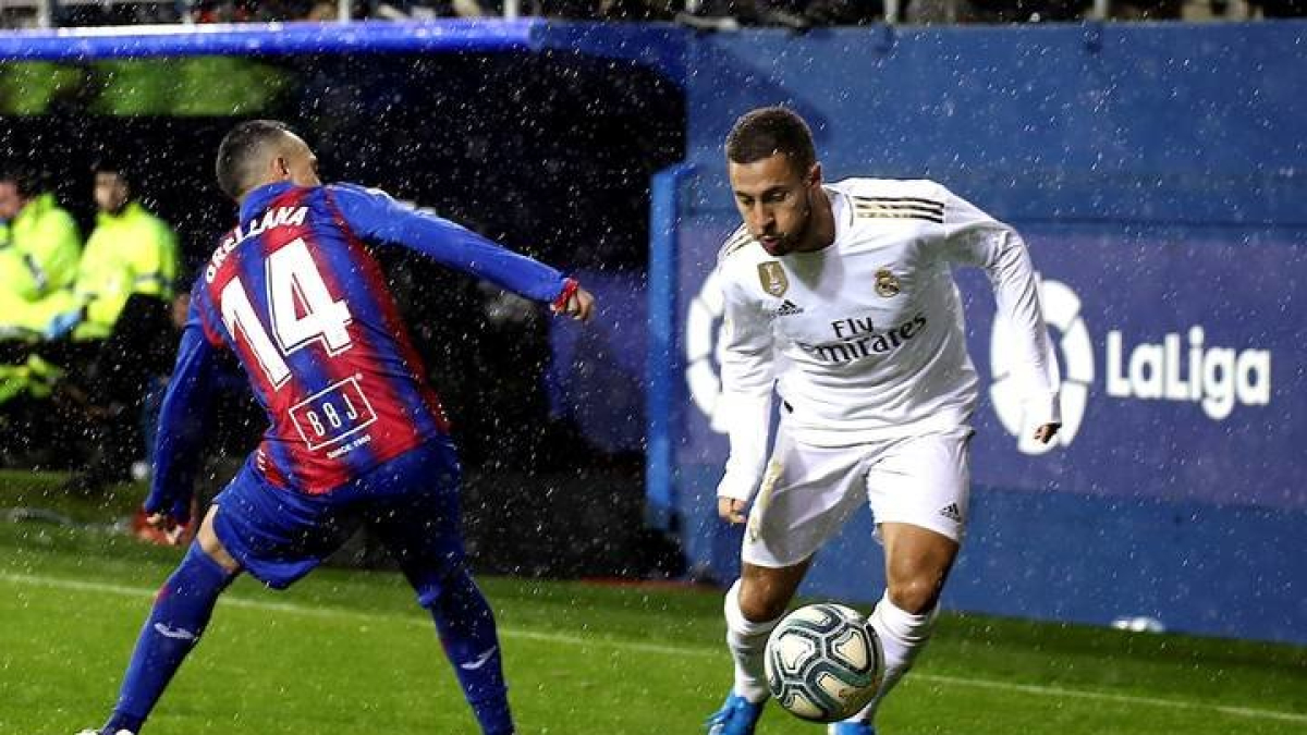 El delantero belga del Real Madrid Eden Hazard (d), conduce el balón ante la presión del centrocampista chileno del Eibar, Fabián Orellana (i) en el partido correspondiente a la décimo tercera jornada de LaLiga Santander, disputada este sábado en el estadio Municipal de Ipurúa. EFE/Juan Herrero.