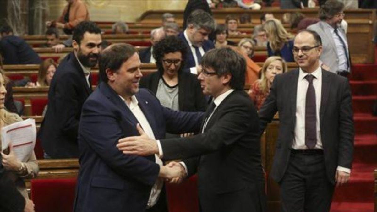 Junqueras y Puigdemont se saludan en el Parlament, en marzo.