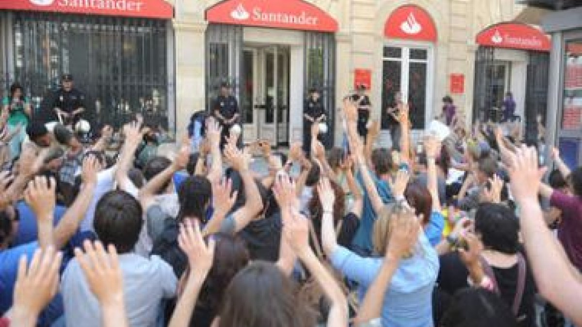 Los activistas alzan las manos simulando ser víctimas de un atraco de la banca.