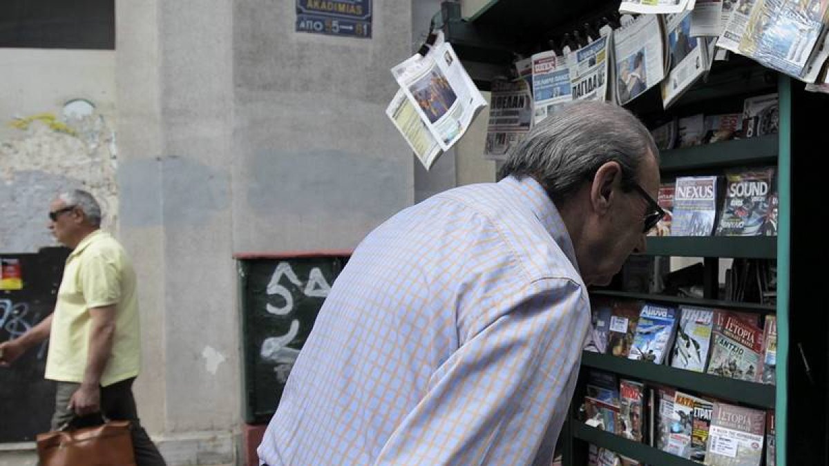 Un hombre mayor lee la prensa en un kiosco