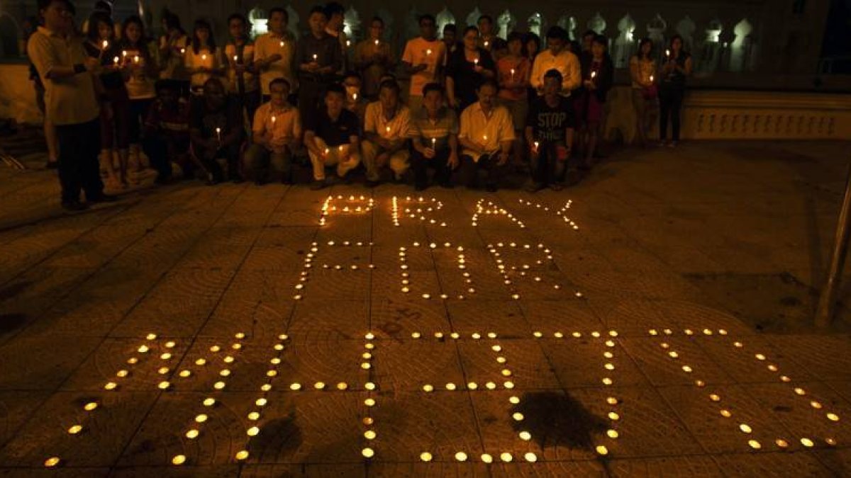 Un grupo de personas rezan ante las velas con la frase