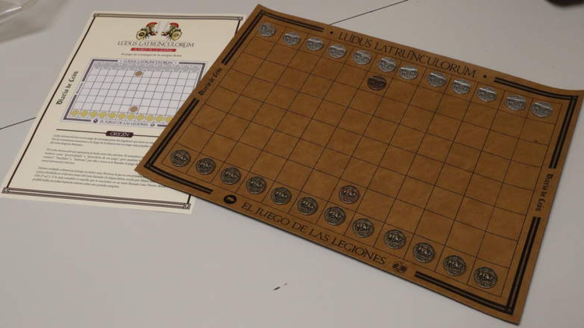 Imagen de las instrucciones y el tablero con las fichas del ‘Ludus Latrunculorum’. Los jugadores deberán elegir uno de los dos bandos (la Legio VI Victrix o la Legio VII Gémina, cada una identificada con su propio emblema) para capturar la ma