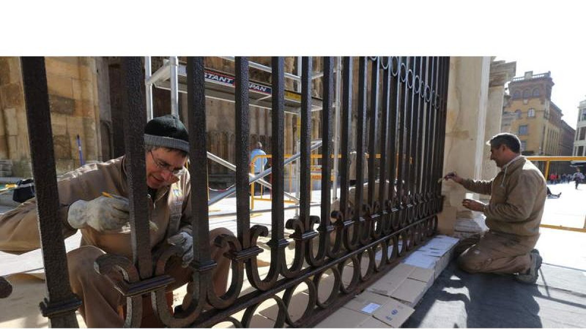 Dos trabajadores pintan las rejas de la Catedral
