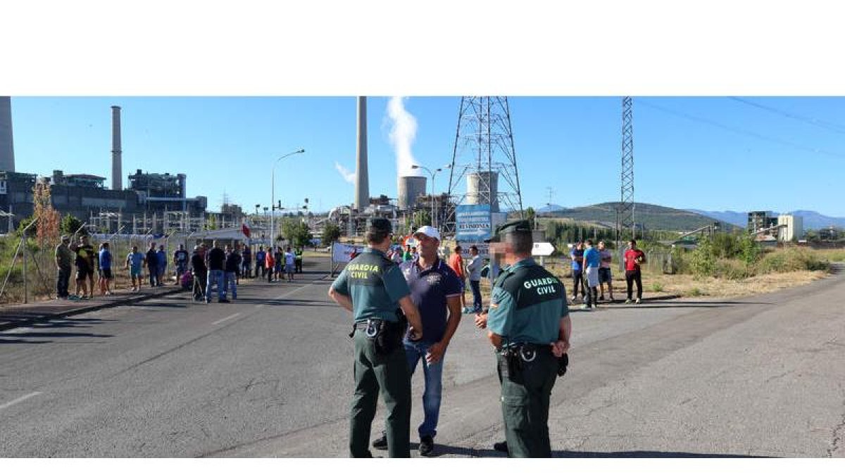 La Guardia Civil habla con uno de los representantes del comité, con los mineros al fondo cortando el paso a la central. ANA F. BARREDO