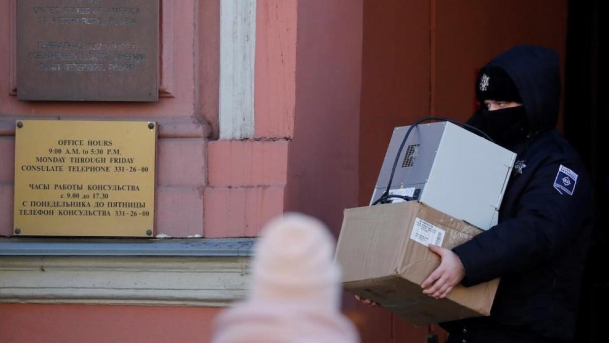 Un agente de seguridad carga con varias cajas a su salida del Consulado General de EEUU en San Petersburgo.