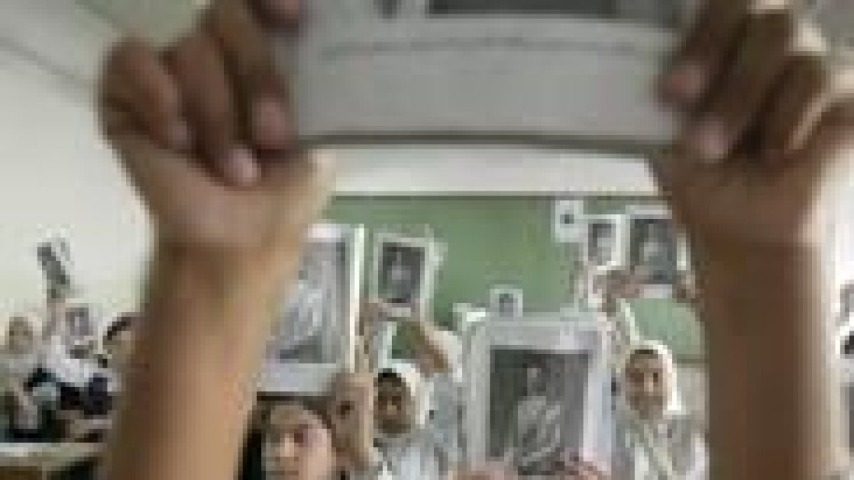 Escolares iraquíes portan retratos de Sadam en el colegio.