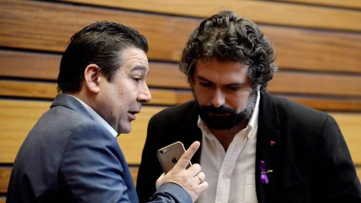 El procurador de UPL, Luis Mariano Santos (i), conversa con el procurador de IU, José Sarrión en las Cortes de Castilla y León.