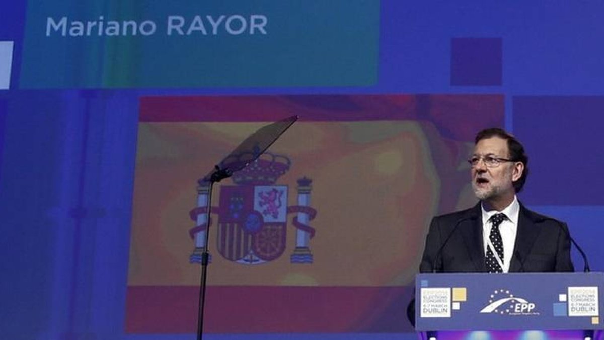 El presidente del Gobierno español, Mariano Rajoy, con la pantalla de fondo donde aparece su apellido mal escrito.