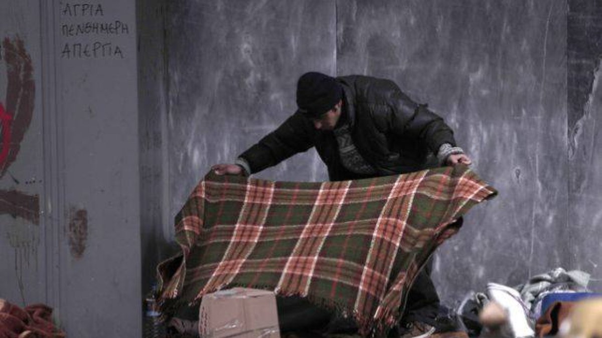 Un 'sintecho' se prepara para pasar la noche en una calle del centro de Atenas, el lunes.