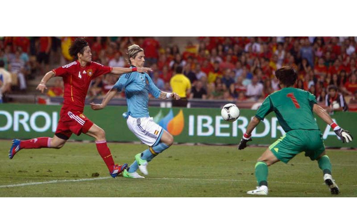 Fernando Torres persigue el balón entre el defensor de la selección de China Zhao Peng y el guardameta Zeng Cheng.