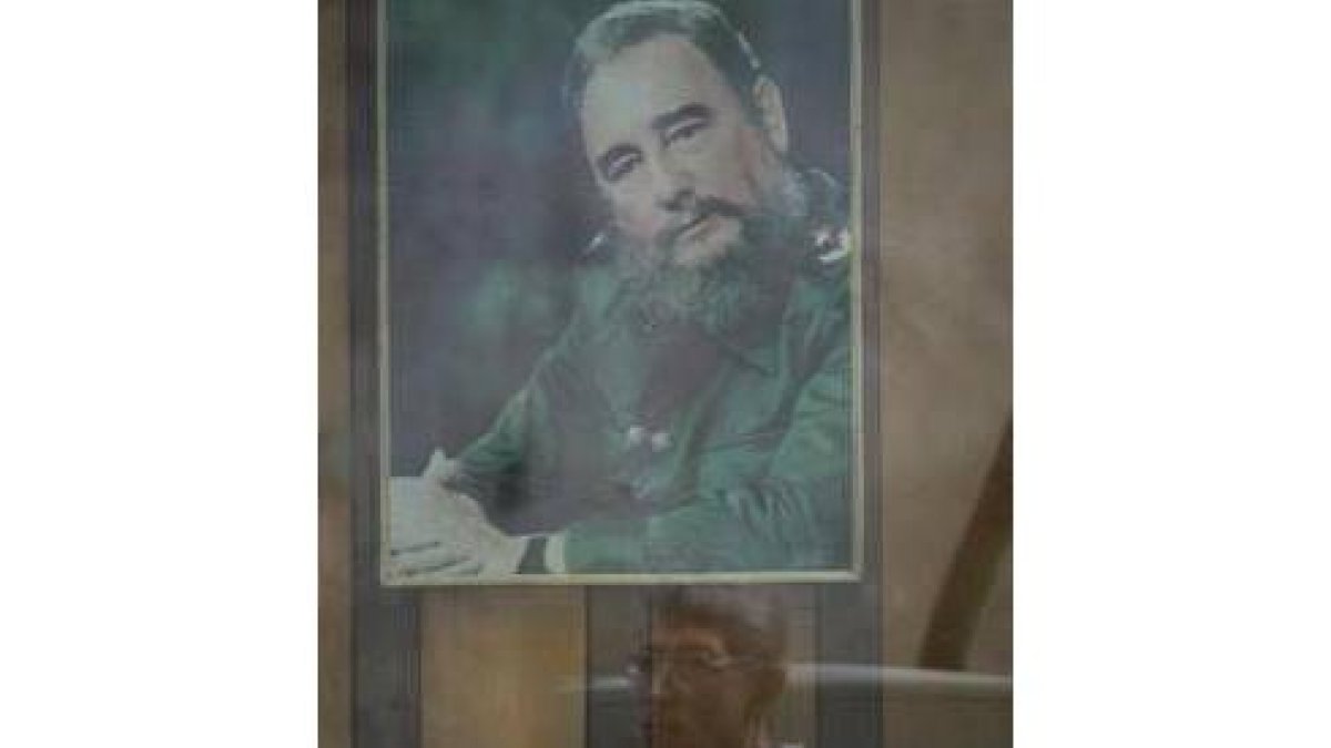 El retrato de Fidel Castro se refleja en una ventana de La Habana al paso de un ciudadano cubano