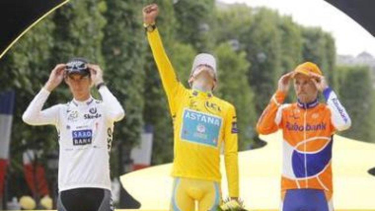 Alberto Contador levanta el puño al cielo parisino para celebrar su victoria, escoltado por Andy Sch