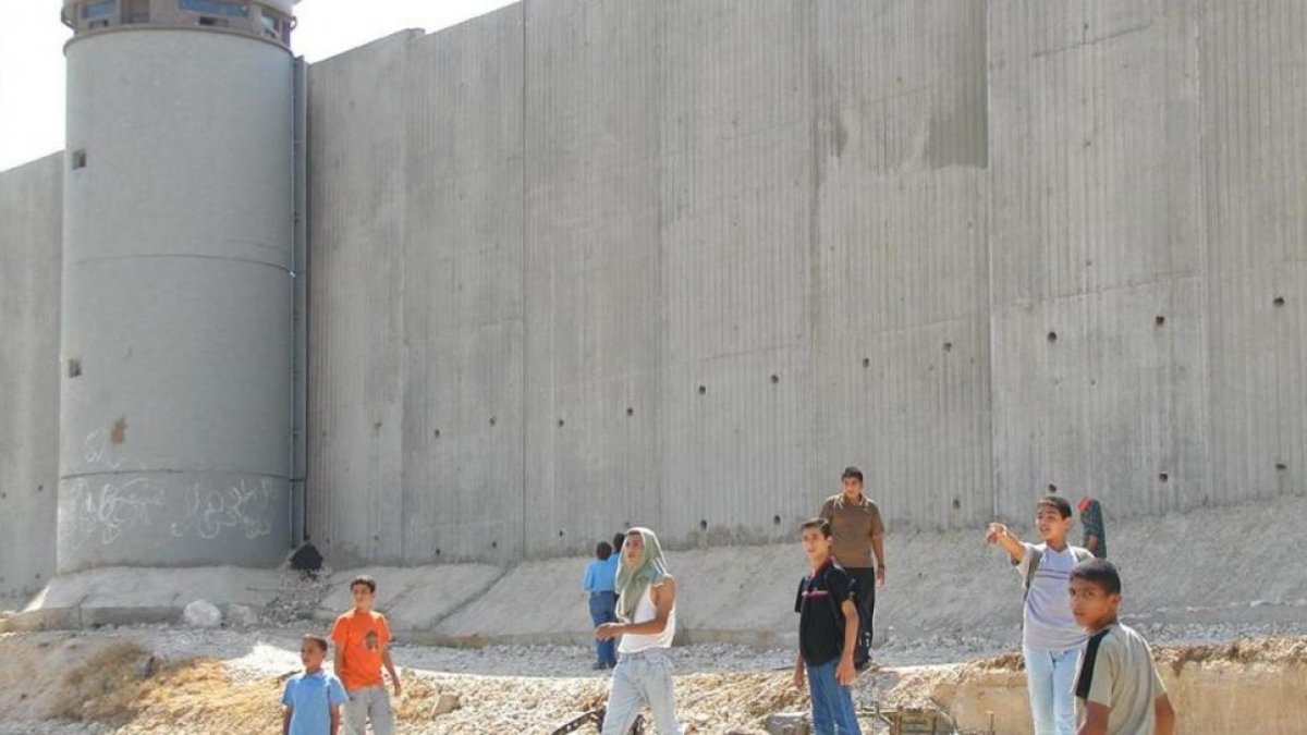 Niños palestinos de camino a la escuela, junto al muro construido por Israel cerca de Qalqilya (Cisjordania).
