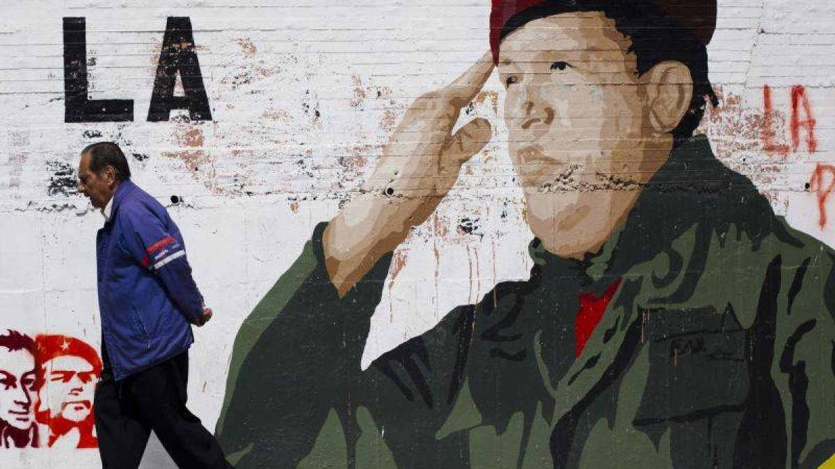 Un hombre pasea frente a un mural de Chavez.