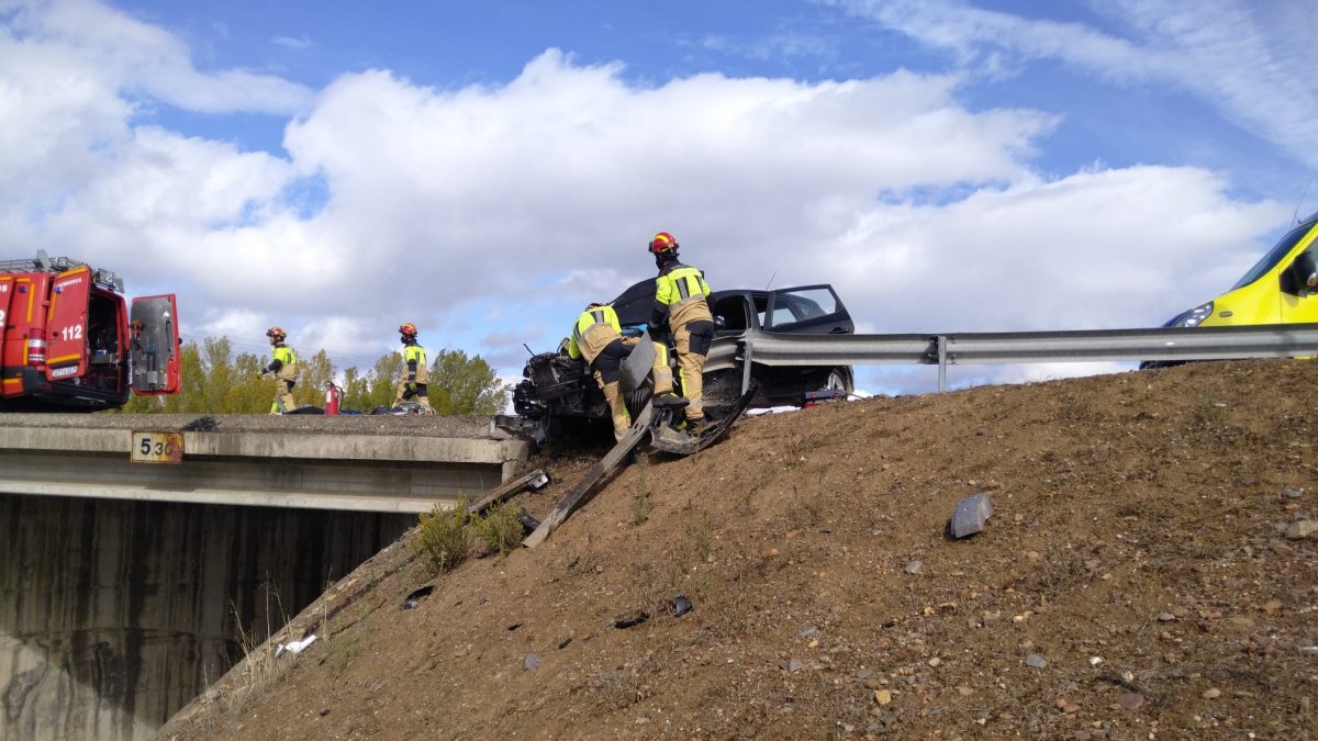 Los bomberos aseguran el coche accidentado para que no caiga por el terraplén. AYUNTAMIENTO DE PONFERRADA