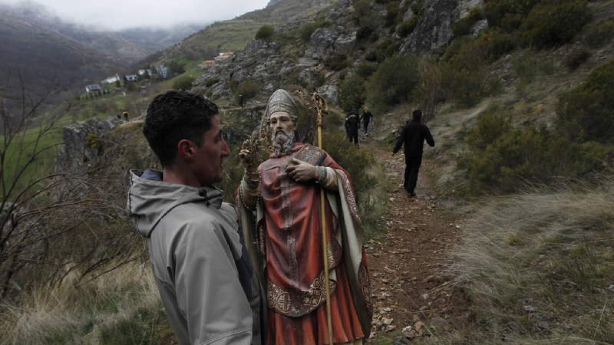 Un joven porta la imagen del santo desde su ermita hasta la campa de la fiesta.