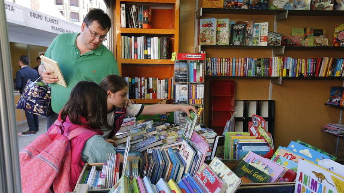 Unos jóvenes lectores curiosean libros en una caseta. RAMIRO