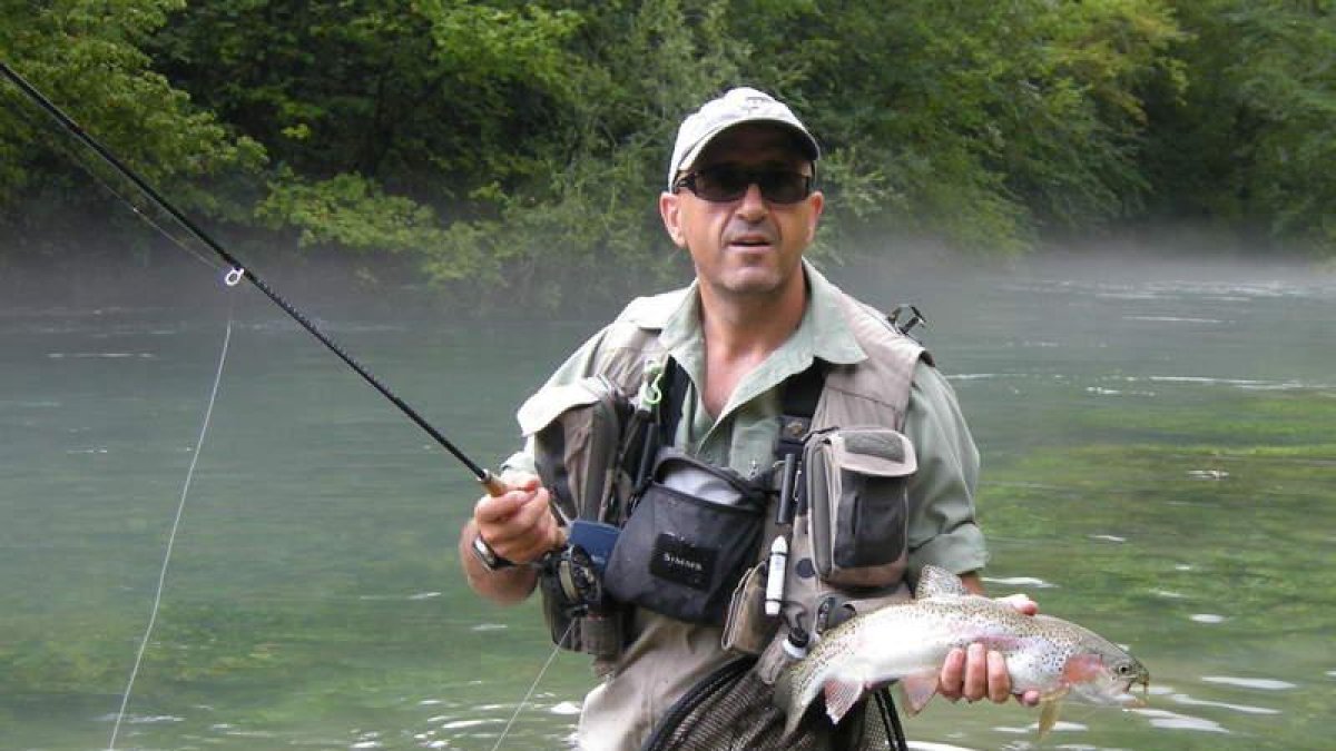 Un pescador sostiene un magnífico ejemplar de trucha arco iris.