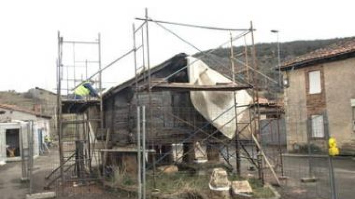 Un operario trabaja en el tejado de la estructura, rodeada de andamios para emprender su restauració