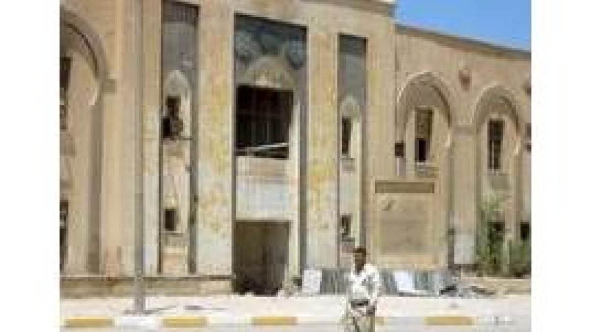 Un hombre pasea junto al Palacio de Gobierno en Diwaniya, saqueado durante la última revuelta