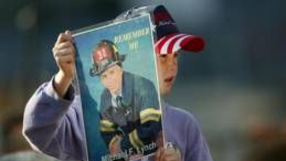 Una niña muestra la fotografía de su padre, bombero, muerto el 11-S