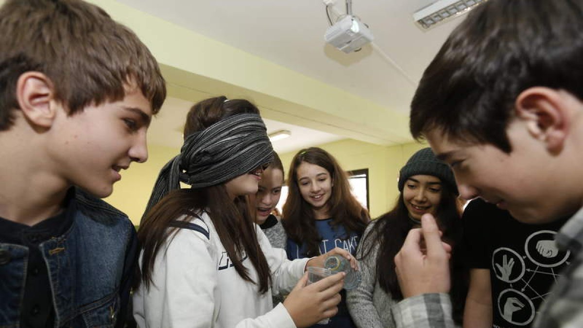 Una estudiante con los ojos vendados intentar echar agua en un vaso