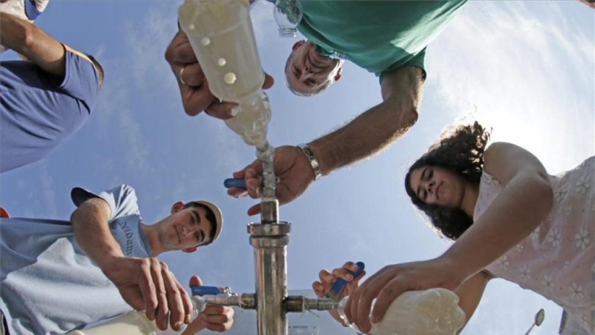Vecinos recogen leche regalada por ganaderos de una cisterna en frente a un centro comercial en el 2015 en Pontevedra.