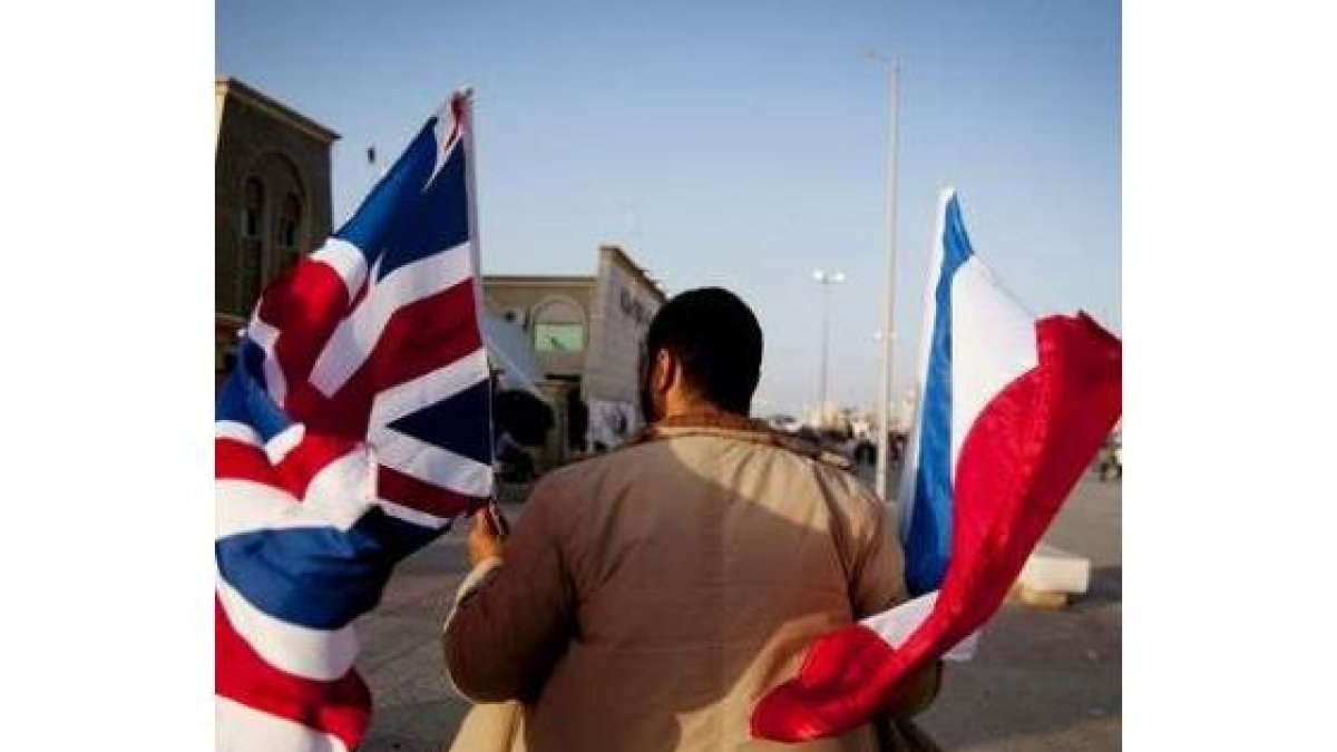 Un hombre con las banderas británica y francesa, en Bengasi.
