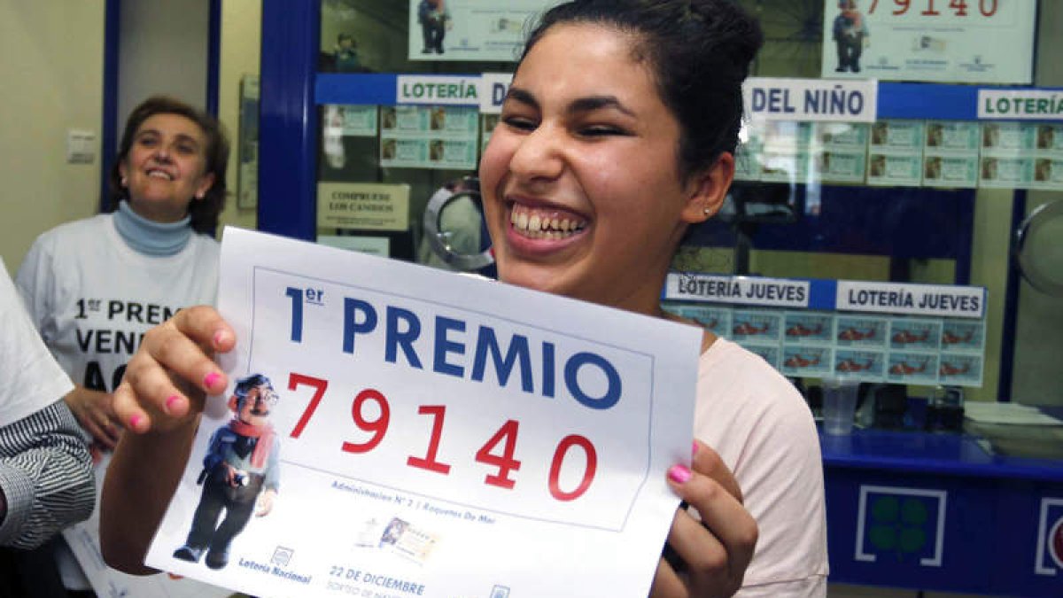 Una joven sonríe con una copia del número 79.140, agraciado con el Gordo de Navidad del Sorteo Extraordinario de la Loteria.