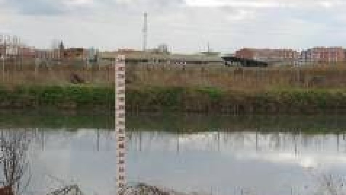 Una de las balsas de decantación y, al fondo, una instalación ganadera en las afueras de la ciudad