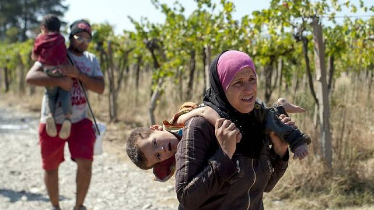 Una mujer carga con su hijo en Macedonia, este viernes.