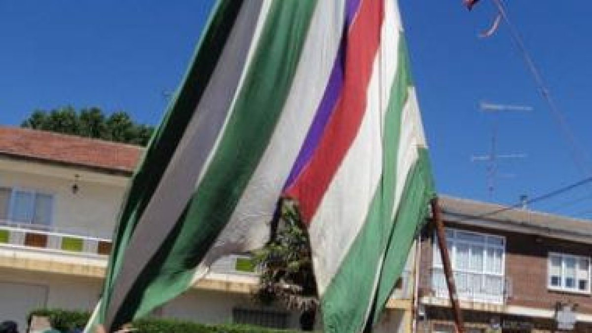 Jóvenes levantan un pendón en la fiesta de la romería de Calzada de la Valdería.
