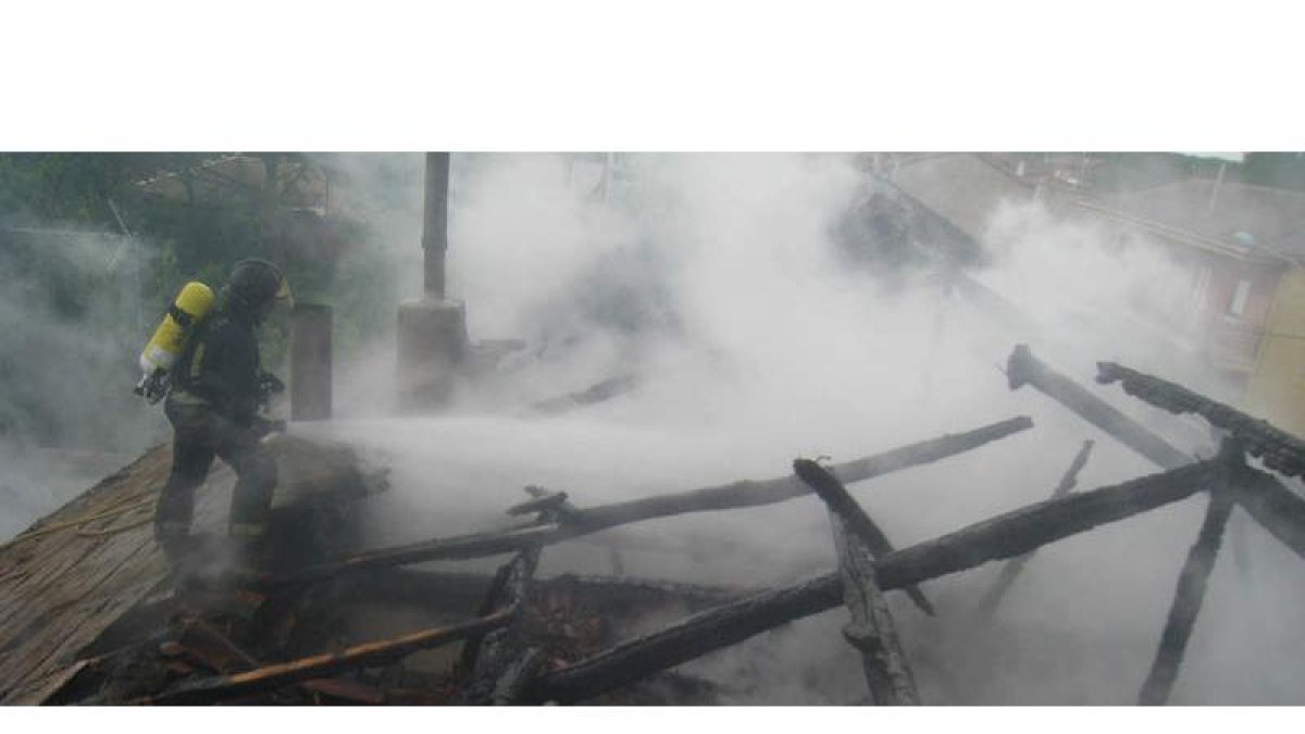 Un bombero trabaja en la extinción del fuego, que provocó la caída del tejado.