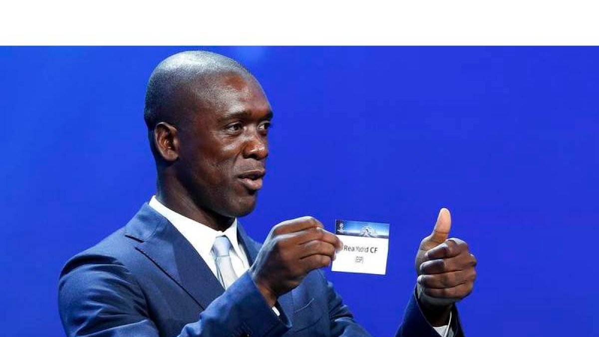 El ex jugador madridista Clarence Seedorf muestra la papeleta del Real Madrid durante el sorteo de la Champions. SEBASTIEN NOGIER